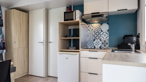 A compact kitchen with a built-in refrigerator, a microwave, and a coffee machine. - Chalet in Nature, Friesland (De Veenhoop)