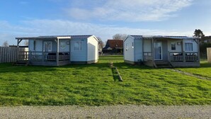 Two mobile homes with porches, a grassy yard, and a gravel path. - Chalet in Nature, Friesland (De Veenhoop)