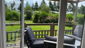 Een overdekt terras met twee grijze fauteuils en een kleine tafel.