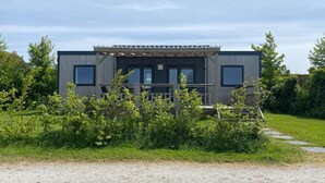 Een modern, tweelaags gebouw met een houten terras en grote ramen.