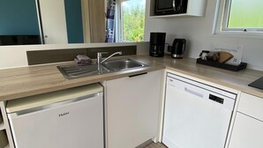 Een kleine keuken met een vaatwasser, een spoelbak, een koffiezetapparaat en een magnetron.