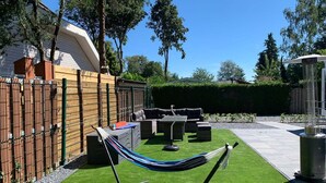 Eine Terrasse mit künstlichem Rasen, Gartenmöbeln und einer Hängematte.