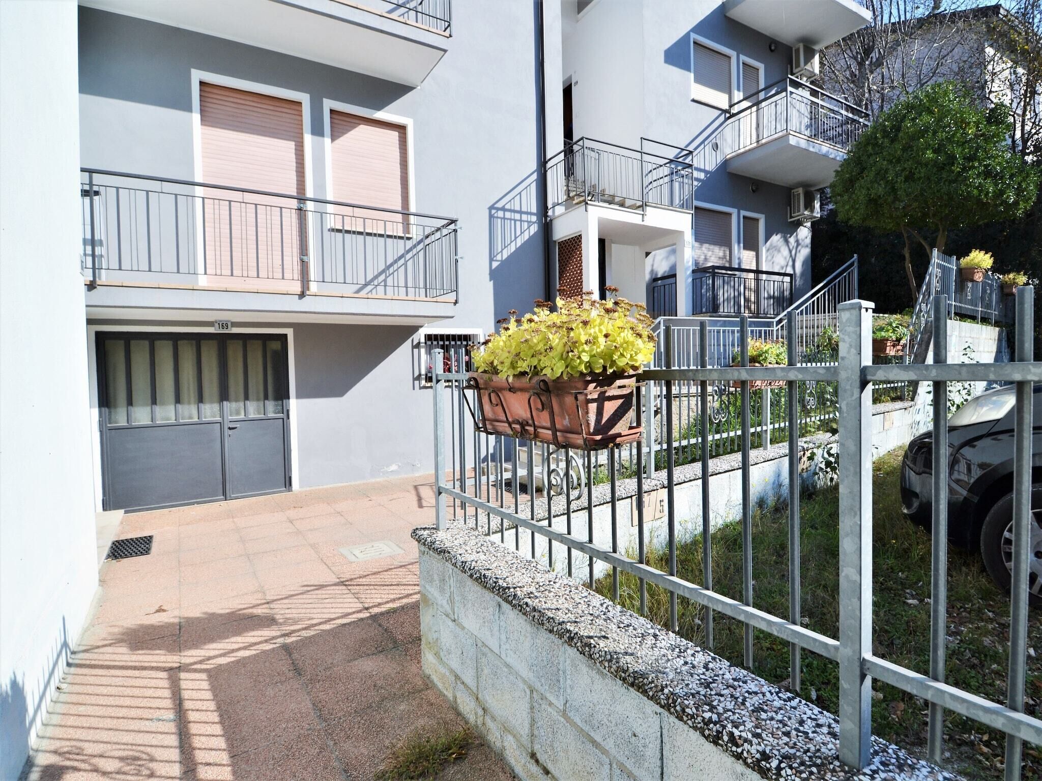 Ein Wohngebäude mit geschlossenem Eingang, einem Balkon mit Blumentopf und einer sichtbaren Hausnummer.