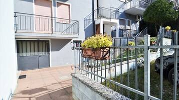 Ein Wohngebäude mit geschlossenem Eingang, einem Balkon mit Blumentopf und einer sichtbaren Hausnummer.