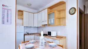 A modern kitchen with white cabinets, a microwave, and a dining table set for four. - Apartment in Rosolina Mare near the Sea (Rosolina Mare (RO))