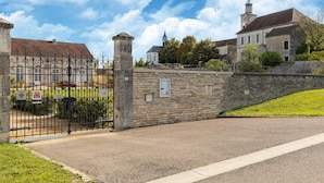A gated entrance to a historic building with a stone wall and a metal gate.