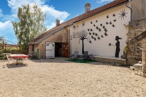 A building with a gravel courtyard, a dining table with chairs, and a mural of a tree and butterflies.