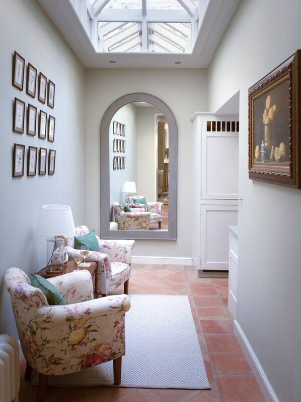 A room with a skylight, a mirror reflecting a dining area, floral-patterned furniture, and framed artwork on the walls. - Kings Road, Chelsea, sleeps 6 (London)