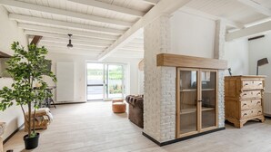 Amplia sala de estar con techo alto, chimenea de piedra, mueble de madera y un ventanal con vistas al exterior.