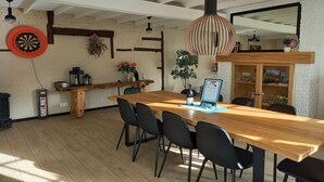Una mesa de comedor de madera con sillas negras, un dardo, una lámpara colgante y una estantería con libros y adornos.