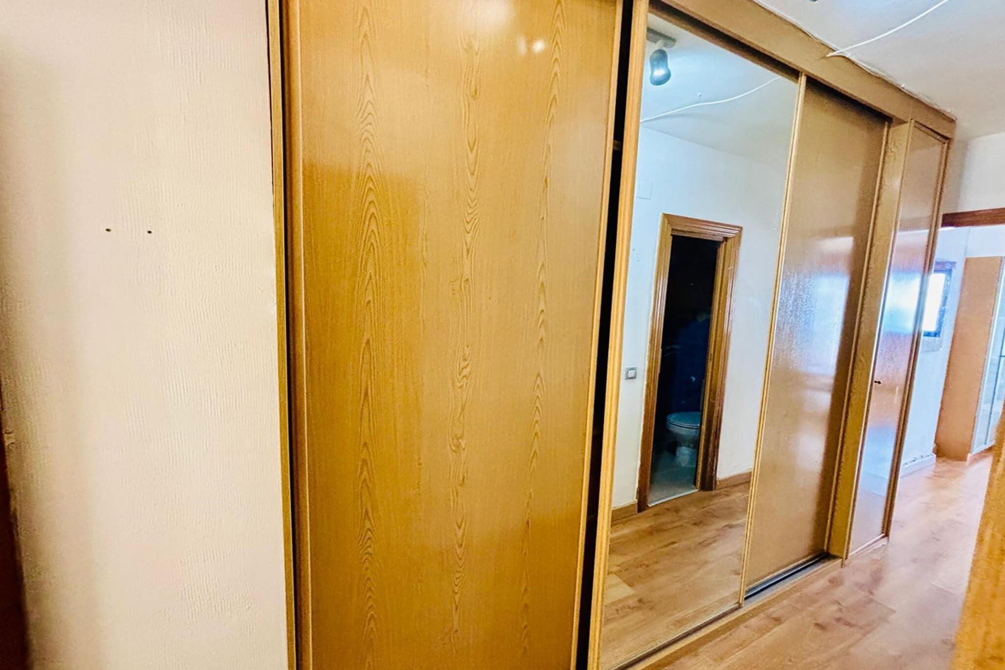 A hallway with wooden flooring and a sliding door.