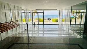 Un moderno vestíbulo de hotel con una pared de vidrio que ofrece vistas a la playa y al mar.