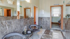 A reception area with marble flooring, a reception desk, and a seating area with a table and chairs.