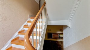 A staircase with wooden steps and white railings, leading to a landing with a small window and a door.