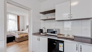 A modern kitchen with white cabinets, a microwave, a sink, and a dishwasher.