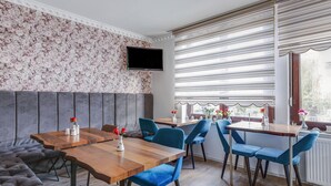 A modern dining area with a wooden table, blue upholstered chairs, and a grey cushioned bench.