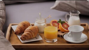 A breakfast tray with croissants, orange juice, milk, and a cup on a wooden table. - La Joséline  (Flayosc)