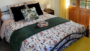 A bedroom with a bed, a bedside table, a hanging light fixture, and a window with curtains. - La Joséline  (Flayosc)