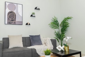 A modern living room with a grey sofa, a coffee table, and a large framed abstract artwork on the wall.