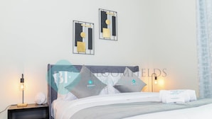 Une chambre bien rangée, avec un lit, des tables de chevet et des œuvres d’art accrochées au mur.