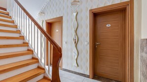 A staircase with wooden steps and a wooden handrail leading to a door with a number plate.