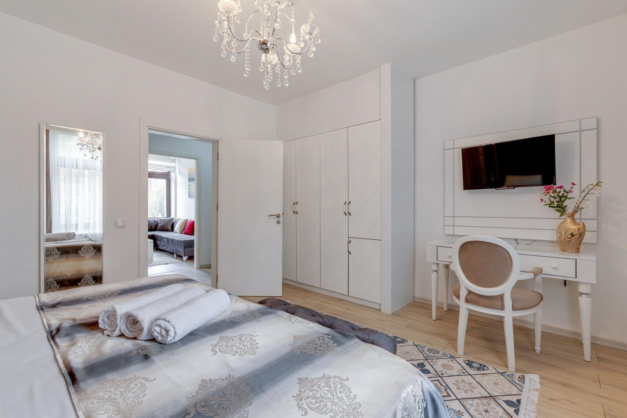A bedroom with a bed, a desk, a chair, a wardrobe, and a mirror.