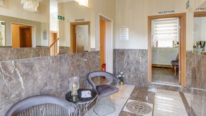 A reception area with marble flooring, a reception desk, and two chairs.