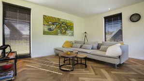 A modern living room with a sofa, two coffee tables, and a painting on the wall.
