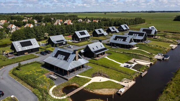 A residential area with modern houses, a canal, and a green landscape.