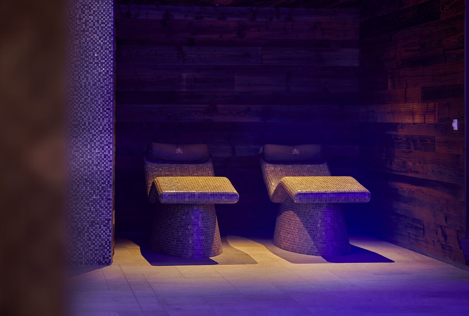 A spa room with two stone benches and a wooden wall.