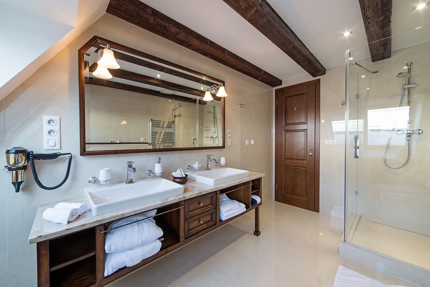 Un baño moderno con dos lavamanos, un espejo grande y una ducha con cerramiento de vidrio.