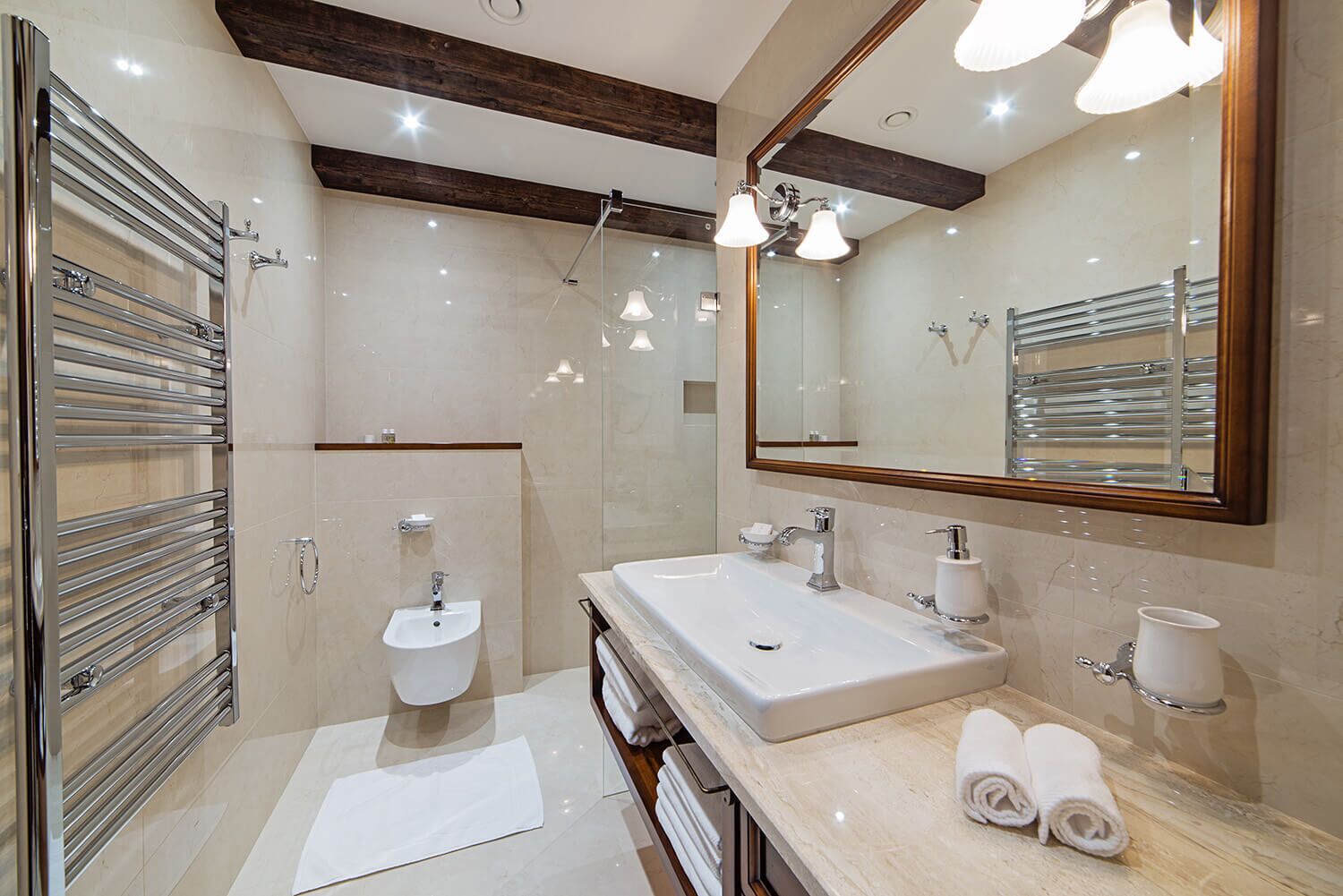 A modern bathroom with a large mirror, two sinks, a shower, and a towel rack.