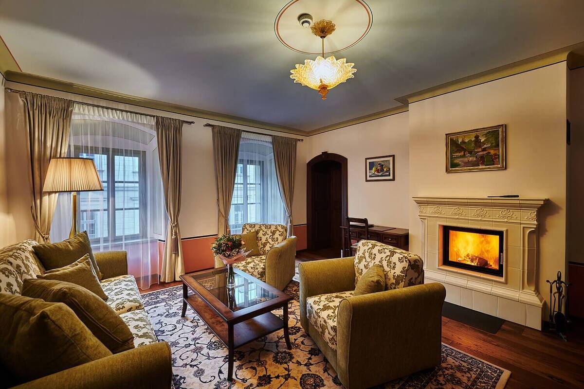 A living room with a fireplace, a sofa set, a coffee table, and a chandelier.