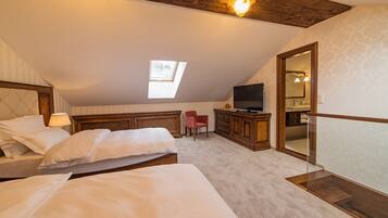 A bedroom with two beds, a TV, a red chair, and a skylight.