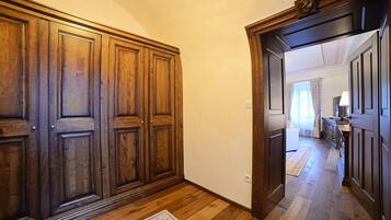 A hallway with wooden paneling, a rug on the floor, and a mirror reflecting a room with a bed and a dresser.