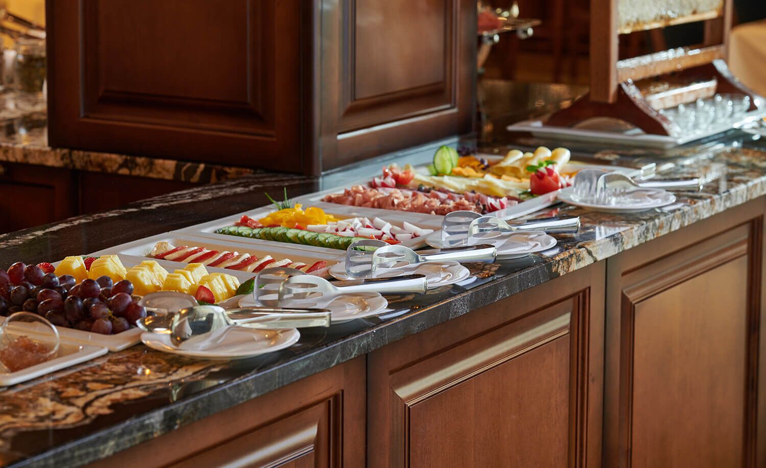 A buffet with various fruits, cheeses, and meats.
