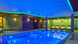 Una piscina con soffitto a stelle, poltrone da relax e pareti in pietra.