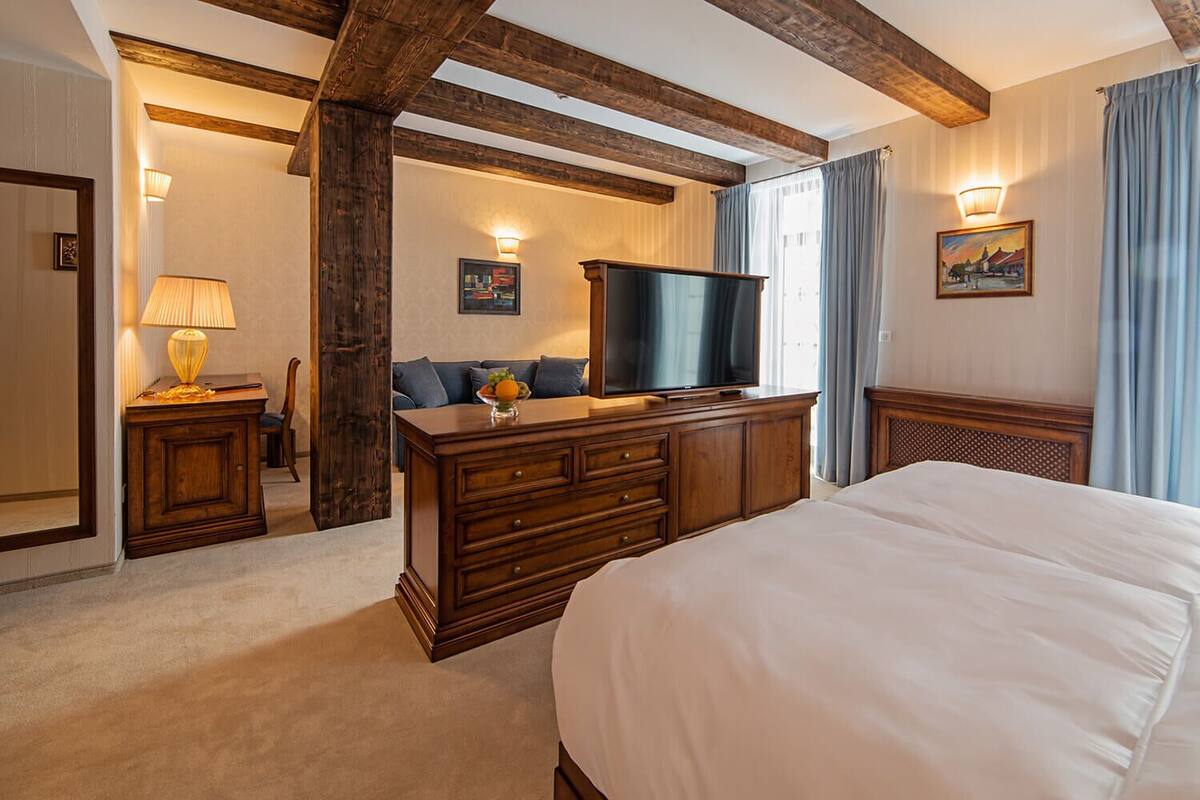 A hotel room with a large bed, wooden furniture, a flat-screen TV, and a view of the outdoors.