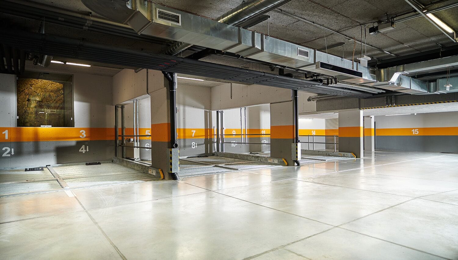 A parking garage with numbered parking spaces and a ventilation system.