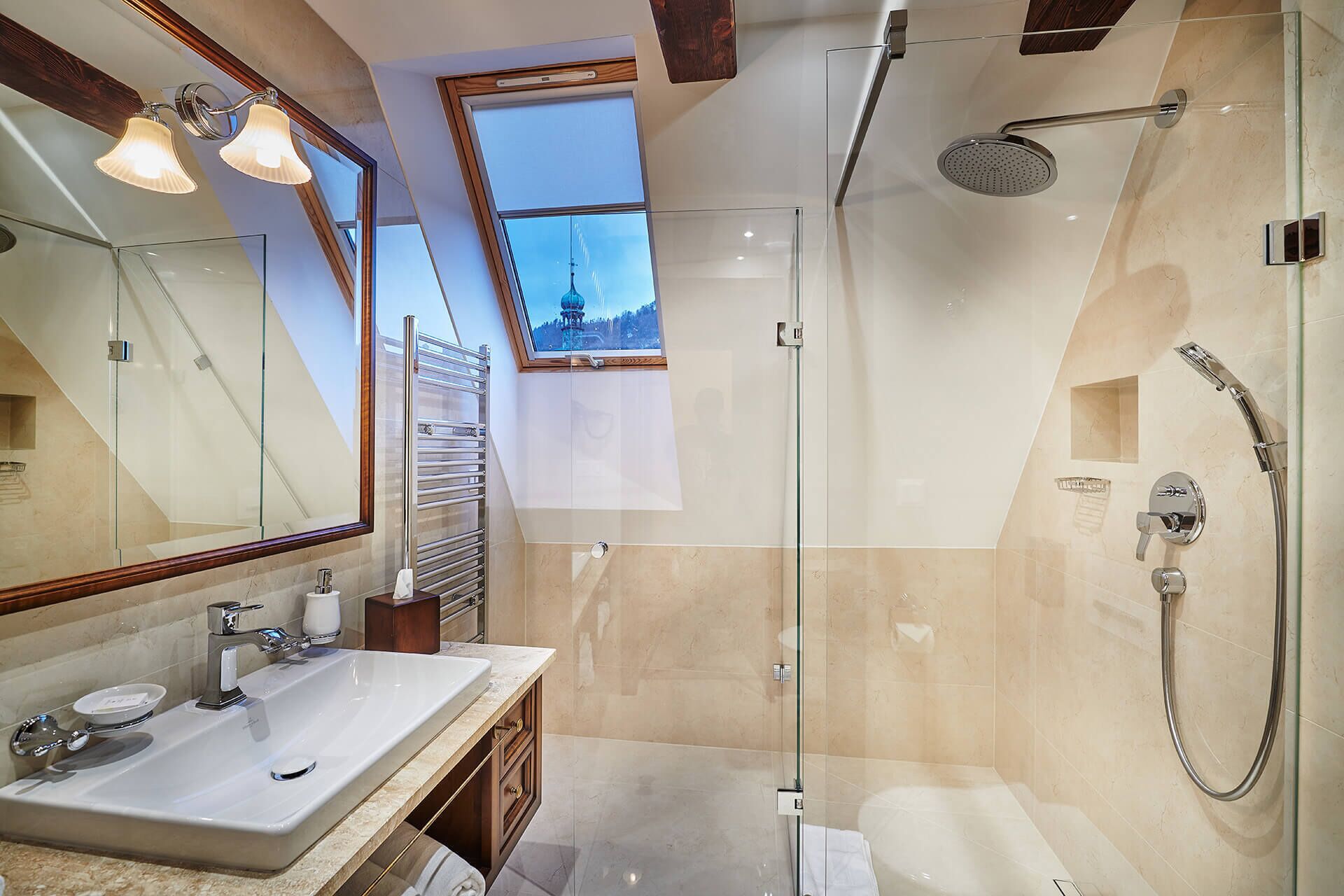A modern bathroom with a glass shower enclosure, a large mirror, and a window providing a view of a mountain.