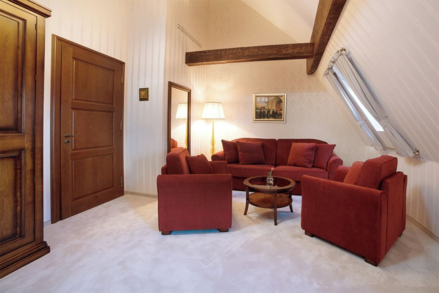 Un salon chaleureux avec un canapé rouge, un meuble en bois et une petite table ronde.