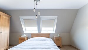 A bedroom with a wooden bed, two bedside tables, a wardrobe, and a skylight.