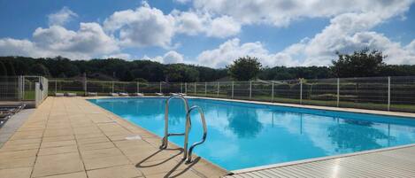 Relax by the pool surrounded by lounge chairs and a metal ladder leading into the water.