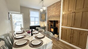 Comedor con chimenea de ladrillo, armarios de madera y mesa lista para seis comensales.