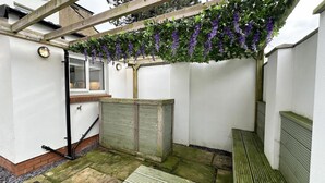 Un espacio de patio cubierto con un pérgola de madera, una fuente de agua y un mueble de almacenamiento de madera.