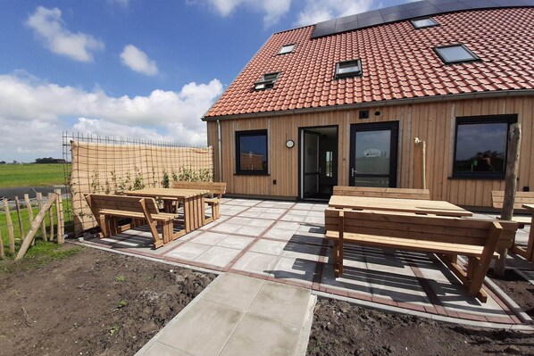 A wooden building with a tiled roof, outdoor seating, and a fenced garden area. - Family-Friendly Villa in Leons (Leons)
