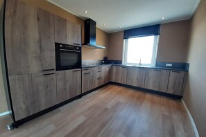 A modern kitchen with wooden cabinets, a built-in oven, and a window providing natural light. - Family-Friendly Villa in Leons (Leons)