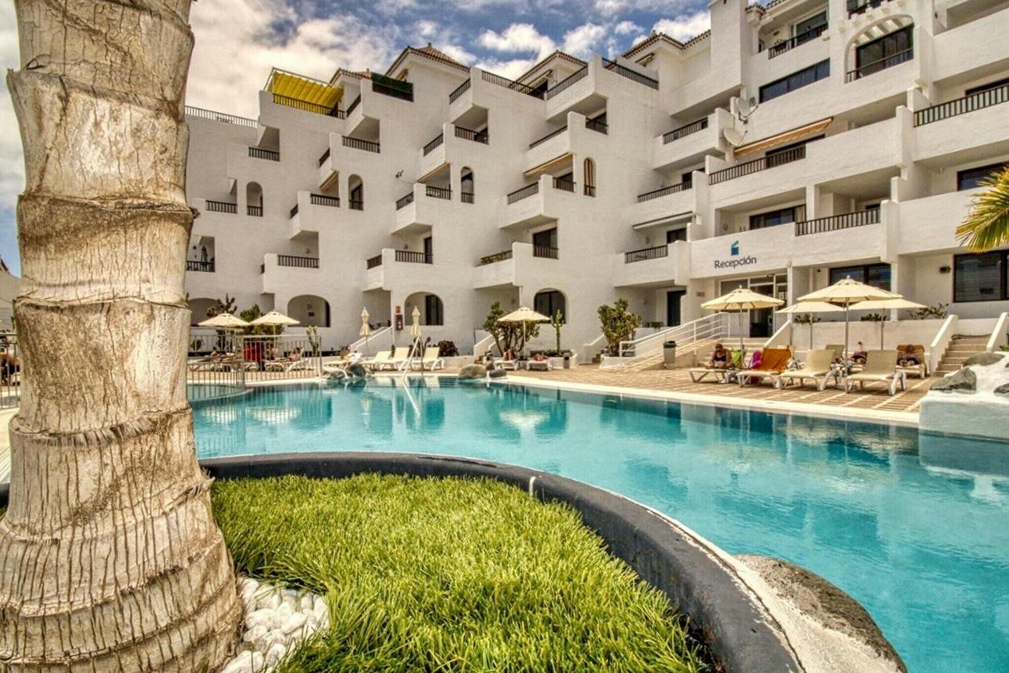 Hotel com piscina, várias varandas e área de recepção.