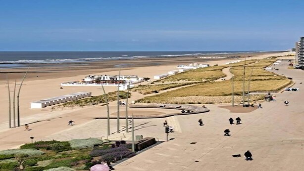 A coastal promenade with a sandy beach, a curved pathway, and a few people walking. - Sleek Stay by the Sea (Middelkerke)