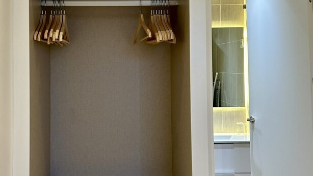 Een inloopkast met houten kleerhangers en een spiegeldeur.